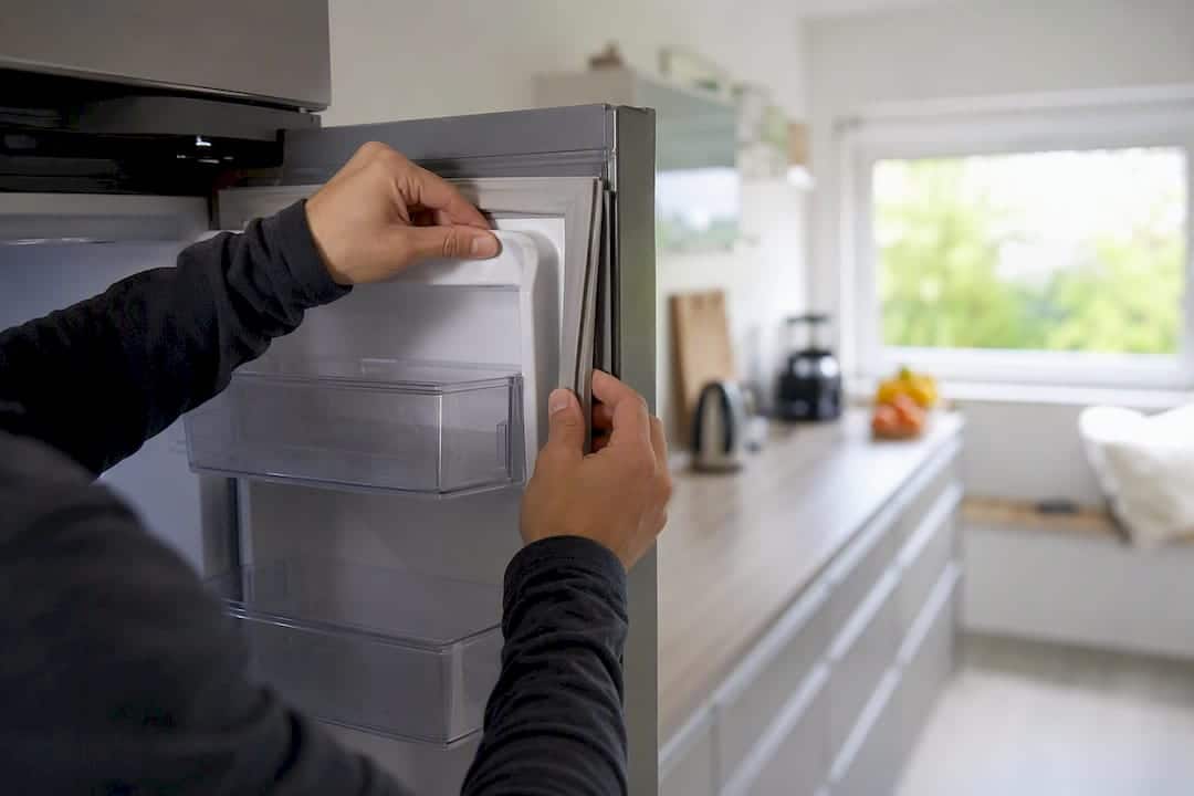 Hand, die die Dichtung der Kühlschranktür überprüft