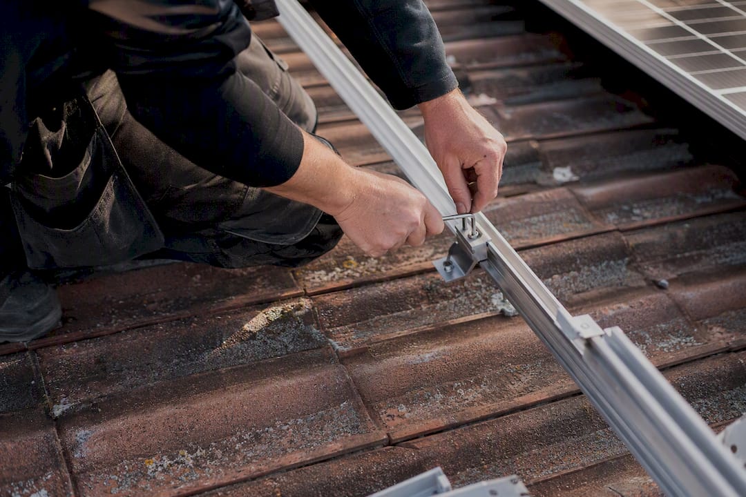 Vorteile von Solarzellen: Was Photovoltaik wirklich bringt 2 Ein Elektriker montiert auf dem Dach eine Befestigung für Solarmodule.
