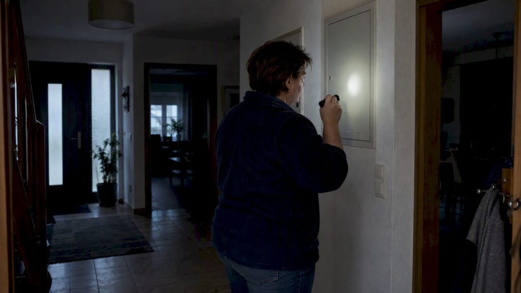 Hausbesitzerin kontrolliert Stromausfall im dunklen Flur