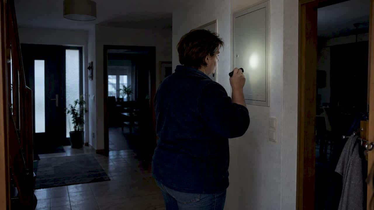 Hausbesitzerin kontrolliert Stromausfall im dunklen Flur